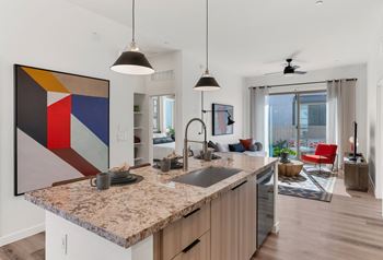 A modern kitchen with a granite countertop and a large abstract painting above it.